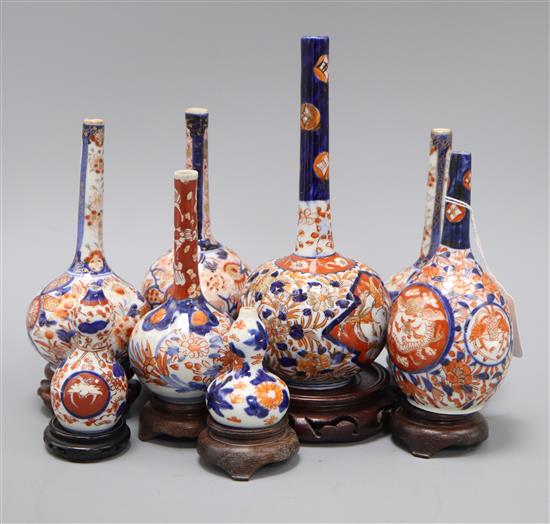 Six Japanese Imari bottle vases and two Imari gourd vases and hardwood stands tallest 22cm